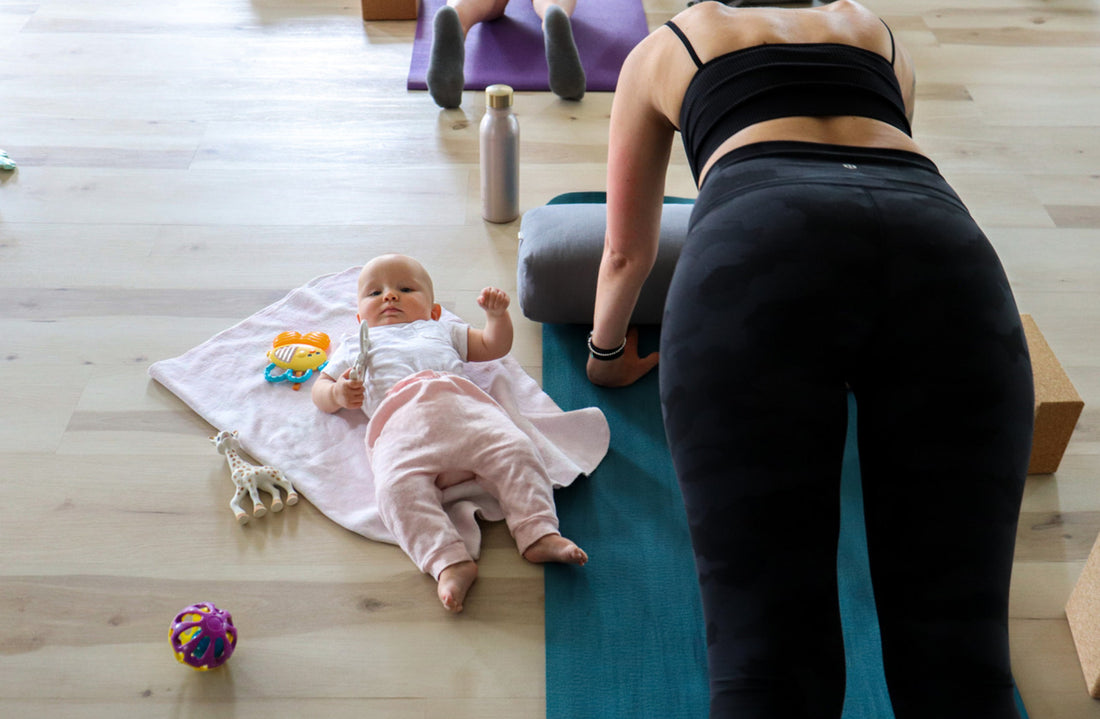 Baby sitting on mat mom doing yoga